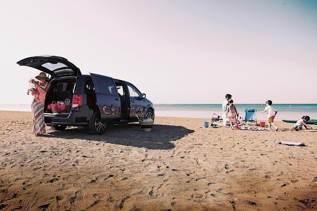 Une famille sur une plage avec le Dodge Grand Caravan 2019.